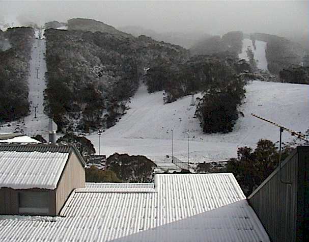 Snow covers roof tops and cars in the village