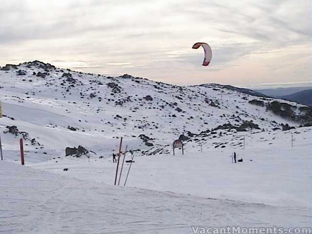 A large kite in a light breeze connected to skier and sled - there's a story there somewhere