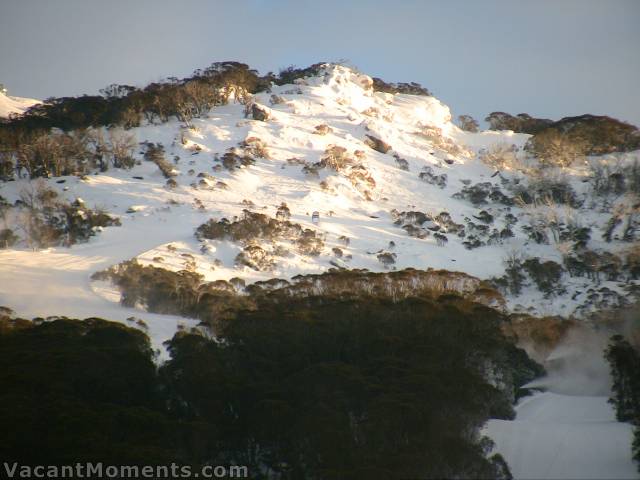 Early rays on Michael's Mistake above snow guns on High Noon