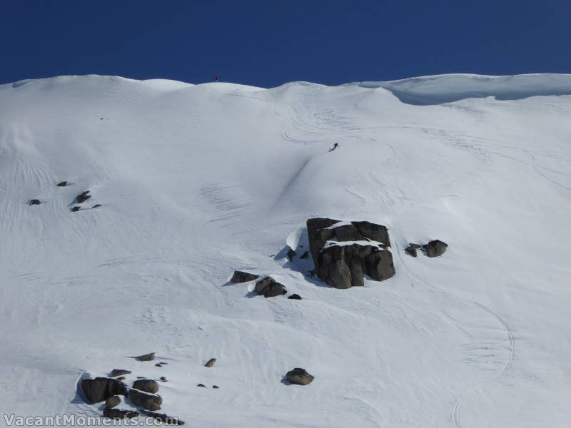 Three young adventurers getting air off the cliffs below the cornice